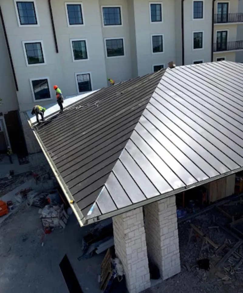 Crew installing standing seam metal roof panels on a commercial project in Saraland
